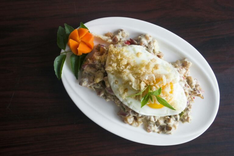 Delicious gourmet fried egg served on a creamy vegetable medley garnished with fresh herbs.